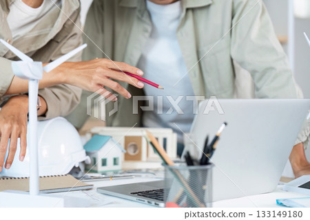 Collaborative Design. Architects discussing plans and ideas with a laptop and model in a modern office. 133149180