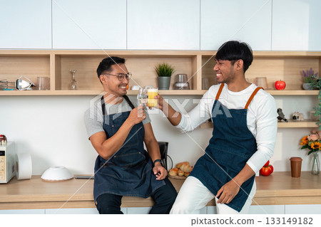 Couple toasting with fresh juice in modern kitchen Couple toasting with fresh juice in modern kitchen 133149182