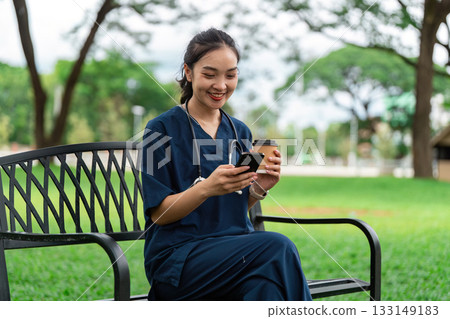 Doctor enjoying coffee break while using smartphone in park 133149183