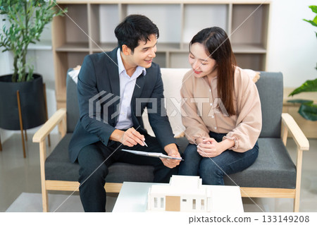 Real Estate Meeting. Agent Explaining Property Details to Client on Couch. 133149208