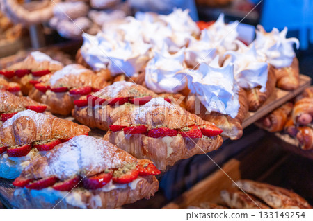 Close-up of freshly baked croissants filled with cream and fresh berries, dusted with powdered sugar. Tasty pastry shot for bakery menus, food blogs and culinary marketing Close-up of freshly baked croissants filled with cream and fresh berries, dusted with powdered sugar. Tasty pastry shot for bakery menus, food blogs and culinary marketing 133149254
