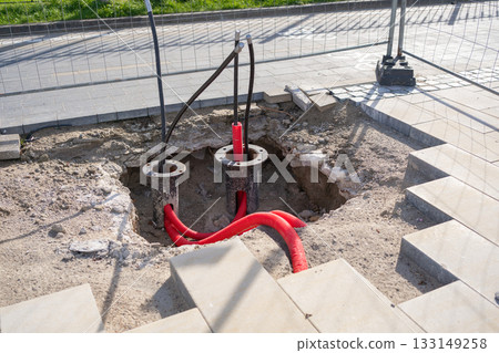 Excavation site with red utility cables and foundation elements exposed. The image documents urban infrastructure development and underground cable installation 133149258