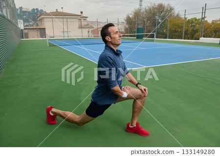 Athlete in Blue Sweatshirt Performing Lunge on Tennis Court for Fitness Training Athlete in Blue Sweatshirt Performing Lunge on Tennis Court for Fitness Training 133149280