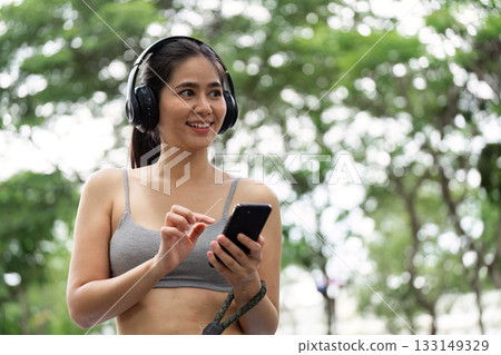 Happy Fitness. Woman Smiling While Using Smartphone Outdoors Happy Fitness. Woman Smiling While Using Smartphone Outdoors 133149329