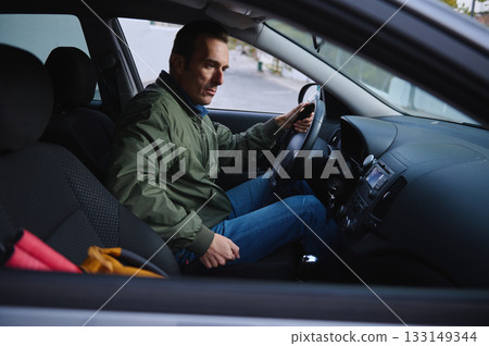 Man Driving Car Inside Vehicle With Focused Expression In A Casual Green Jacket 133149344