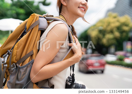 Travel. Young woman with backpack smiling on busy city street. 133149456