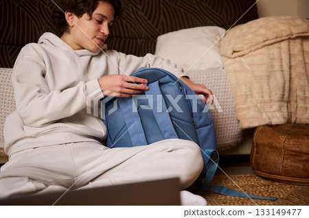 Teen Boy Packing Backpack At Home For School Day - Casual, Relaxed Moment Teen Boy Packing Backpack At Home For School Day - Casual, Relaxed Moment 133149477