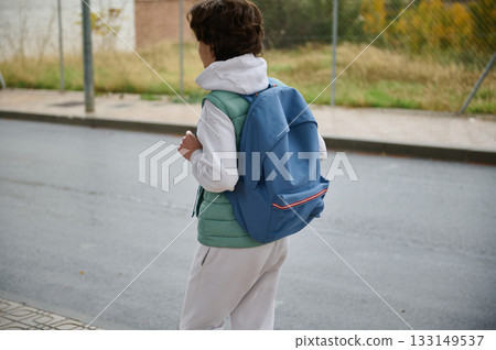 Teenage Boy With Blue Backpack Walking Away On Street In Casual Hoodie And Vest 133149537