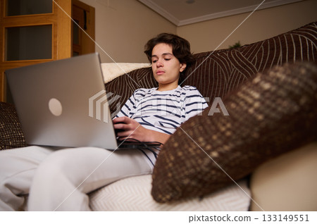 Teenage Boy Relaxing on Couch Using Laptop at Home, Gen Z Student 133149551