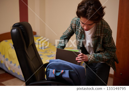 Teenager Organizing Backpack in Bedroom, Preparing for School Day Teenager Organizing Backpack in Bedroom, Preparing for School Day 133149795
