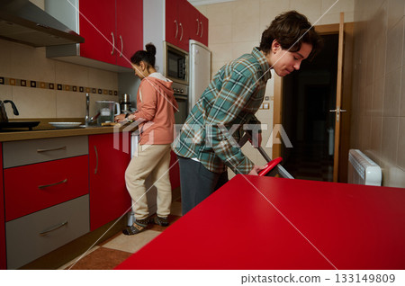 Teenagers Clean Kitchen Together: Casual Family Moment in Red Modern Kitchen Teenagers Clean Kitchen Together: Casual Family Moment in Red Modern Kitchen 133149809