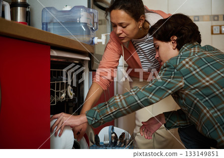 Two People Load a Dishwasher in a Cozy Kitchen, Demonstrating Teamwork and Responsibility Two People Load a Dishwasher in a Cozy Kitchen, Demonstrating Teamwork and Responsibility 133149851