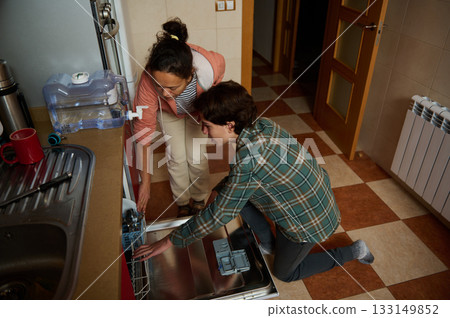 Two Friends Loading Dishwasher In Modern Kitchen For A Cozy Home After Dinner Two Friends Loading Dishwasher In Modern Kitchen For A Cozy Home After Dinner 133149852