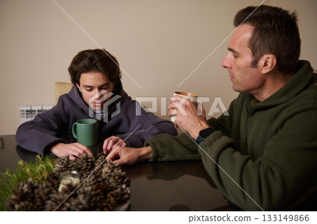 Father And Son Share Coffee At Table In Warm Home Setting 133149866