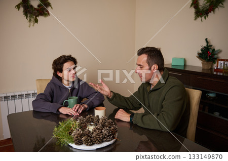Father And Son Talk At The Christmas Dinner Table In A Cozy Home Setting 133149870