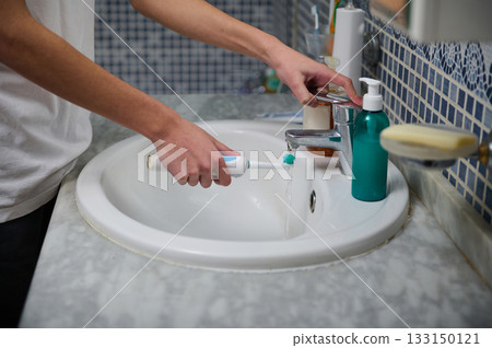 Person Brushing Teeth at Bathroom Sink With Toothbrush and Toothpaste Person Brushing Teeth at Bathroom Sink With Toothbrush and Toothpaste 133150121