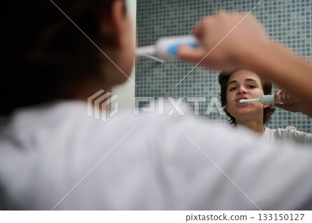 Teenage Boy Brushing Teeth in Mirror Before School in Bright Bathroom Teenage Boy Brushing Teeth in Mirror Before School in Bright Bathroom 133150127
