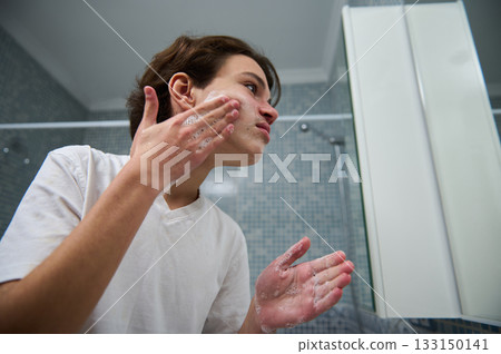 Teen Boy Applies Face Wash In Bathroom For Skincare Routine Teen Boy Applies Face Wash In Bathroom For Skincare Routine 133150141
