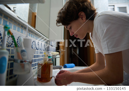 Teenager Washing Hands At Bathroom Sink During Morning Routine Teenager Washing Hands At Bathroom Sink During Morning Routine 133150145