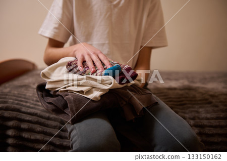 Teenager Folding Laundry on the Bed, Quiet Home Moment of Chore and Comfort Teenager Folding Laundry on the Bed, Quiet Home Moment of Chore and Comfort 133150162