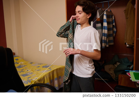 Teenage Boy Folding Clothes in Dorm Room, Casual Moment of Daily Life and Prep Teenage Boy Folding Clothes in Dorm Room, Casual Moment of Daily Life and Prep 133150200