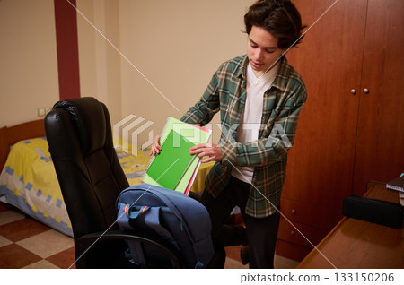 Teen Boy Organizing School Supplies in Bedroom for Study Day Teen Boy Organizing School Supplies in Bedroom for Study Day 133150206