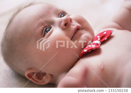 4 months old infant baby boy at changing table, detail on his head, red white dot bow over neck 133150238