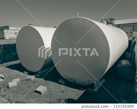 Large storage tanks near an industrial site with clear skies and sunlight shining during the midday Large storage tanks near an industrial site with clear skies and sunlight shining during the midday 133150304