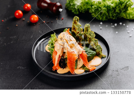 Smoked salmon salad with poached egg, hollandaise and spinach waffles on black plate Smoked salmon salad with poached egg, hollandaise and spinach waffles on black plate 133150778