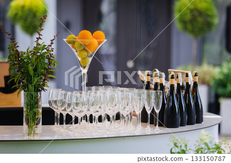 Outdoor champagne bar with citrus centerpiece, glass flutes and bottles ready for service Outdoor champagne bar with citrus centerpiece, glass flutes and bottles ready for service 133150787