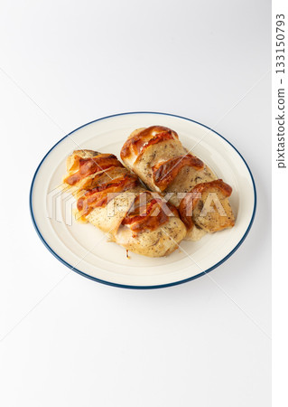 Hasselback chicken breasts baked with tomato and melted cheese on a plate, isolated Hasselback chicken breasts baked with tomato and melted cheese on a plate, isolated 133150793