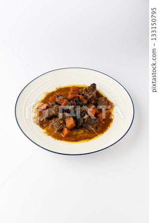 Beef stew with carrots and prunes in rich gravy, served on plate, isolated on white Beef stew with carrots and prunes in rich gravy, served on plate, isolated on white 133150795