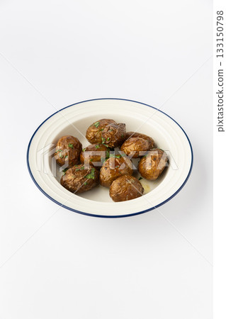 Roasted baby potatoes with fresh herbs in a white bowl on a clean studio background 133150798
