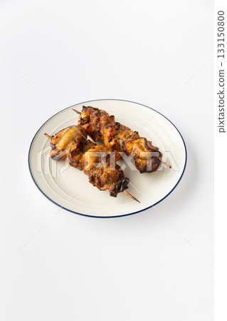 Grilled chicken skewers on a white plate, studio shot of kebab shashlik ready to serve 133150800