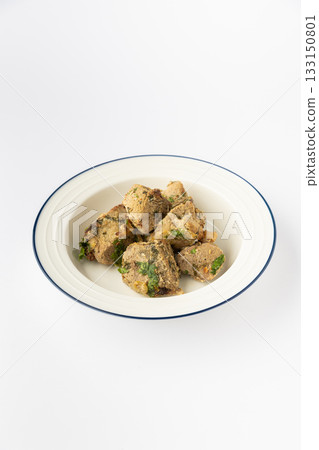 Roasted meat bites with herbs on plate, rustic home cooking, studio photo on white 133150801