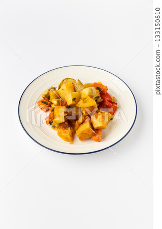 Roasted vegetable medley on plate: golden potatoes, carrots, peppers, zucchini, studio isolated 133150810
