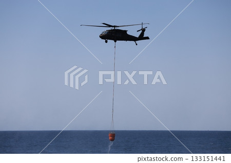 Bucket carrying helicopter.a helicopter scoops up water from the sea. High quality photo Bucket carrying helicopter.a helicopter scoops up water from the sea. High quality photo 133151441