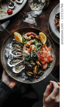 Deluxe seafood platter with fresh oysters, grilled shrimp, smoked salmon and crispy seafood bites. Served on ice with creamy sauce and herbs. Perfect dish for elegant gatherings and fine dining 133152766