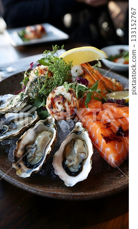 Elegant seafood plate featuring fresh oysters, grilled shrimp, mussels and delicate smoked salmon. Chilled on ice with lemon and arugula. Dish for seafood lovers and gourmet food content Elegant seafood plate featuring fresh oysters, grilled shrimp, mussels and delicate smoked salmon. Chilled on ice with lemon and arugula. Dish for seafood lovers and gourmet food content 133152767