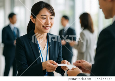 辦公室裡，帶著微笑的日本職業婦女交換名片。 133153452