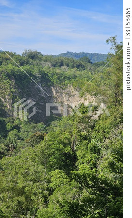 A stunning viewpoint at Panorama Ngarai Sianok showcases lush greenery, towering trees, and a majestic mountain under the clear blue sky, offering a peaceful harmony. A stunning viewpoint at Panorama Ngarai Sianok showcases lush greenery, towering trees, and a majestic mountain under the clear blue sky, offering a peaceful harmony. 133153665