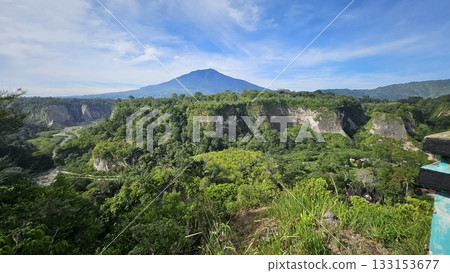 A stunning viewpoint at Panorama Ngarai Sianok showcases lush greenery, towering trees, and a majestic mountain under the clear blue sky, offering a peaceful harmony. 133153677