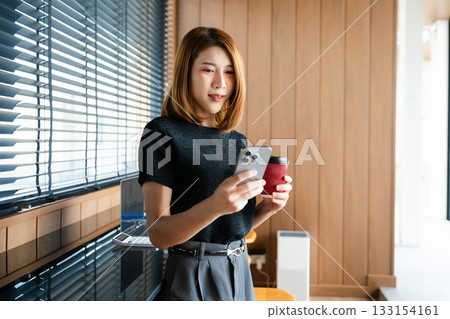 Asian businesswoman on smartphone while reviewing clipboard and laptop in a modern remote office. Asian businesswoman on smartphone while reviewing clipboard and laptop in a modern remote office. 133154161