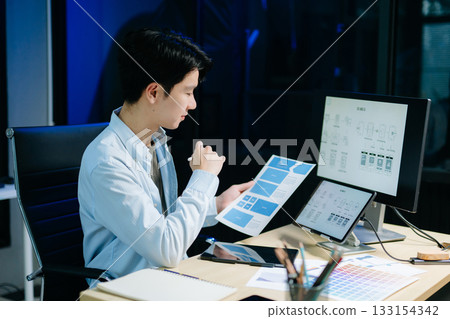 Asian male designer pointing at UX wireframes on screen and tablet in modern office. Ideal for themes in UI UX, digital product design, software Asian male designer pointing at UX wireframes on screen and tablet in modern office. Ideal for themes in UI UX, digital product design, software 133154342