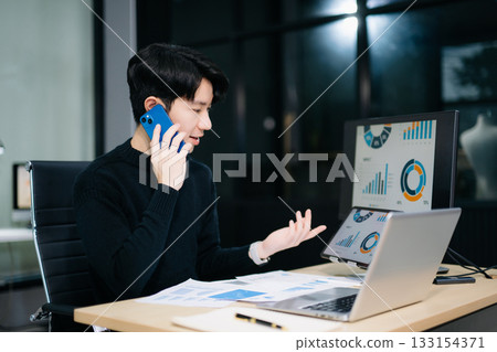 Asian man using laptop and tablet while sitting at her working place. Concentrated at work. 133154371