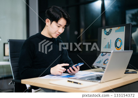 Asian man using laptop and tablet while sitting at her working place. Concentrated at work. 133154372