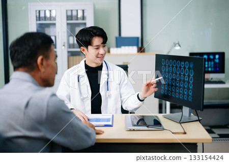 Friendly doctor discussing brain scan results with patient on screen. Health consultation, neurology, diagnosis, and care in clinic Friendly doctor discussing brain scan results with patient on screen. Health consultation, neurology, diagnosis, and care in clinic 133154424