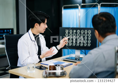 Friendly doctor discussing brain scan results with patient on screen. Health consultation, neurology, diagnosis, and care in clinic Friendly doctor discussing brain scan results with patient on screen. Health consultation, neurology, diagnosis, and care in clinic 133154427