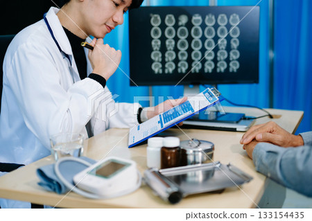 Doctor discusses brain scan results with patient using screen and clipboard.  health care, neurology, diagnosis 133154435