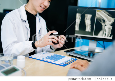 Asian doctor discusses knee X-ray results with senior patient in modern clinic. Concept of orthopedic consultation, bone care, health diagnosis Asian doctor discusses knee X-ray results with senior patient in modern clinic. Concept of orthopedic consultation, bone care, health diagnosis 133154503